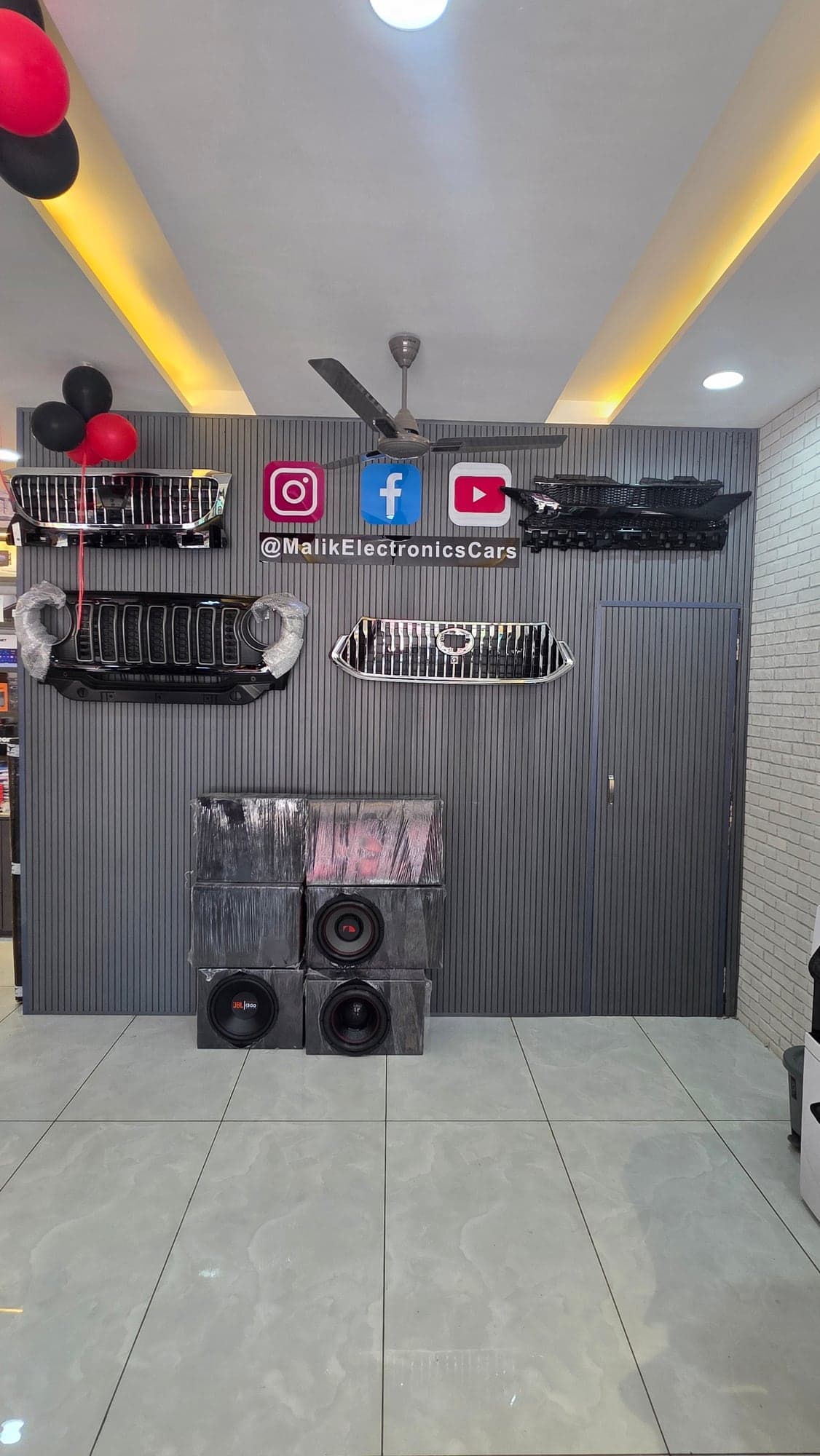 Charcoal vertical fluted wall displaying car grilles and subwoofers, Malik Electronics showroom interior, Ludhiana