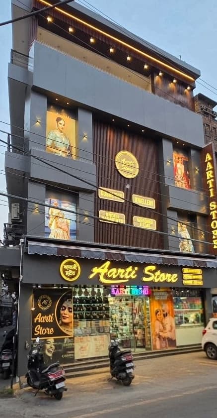 Aarti Store facade after redesign in Ludhiana — ACP cladding, charcoal vertical louvers and warm LED lighting