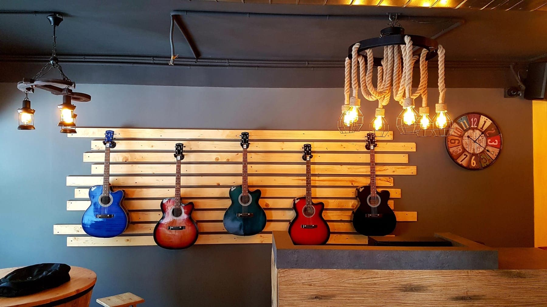 Acoustic guitars mounted on a wooden slat wall beside a rope chandelier, FiTreat restaurant, Ludhiana
