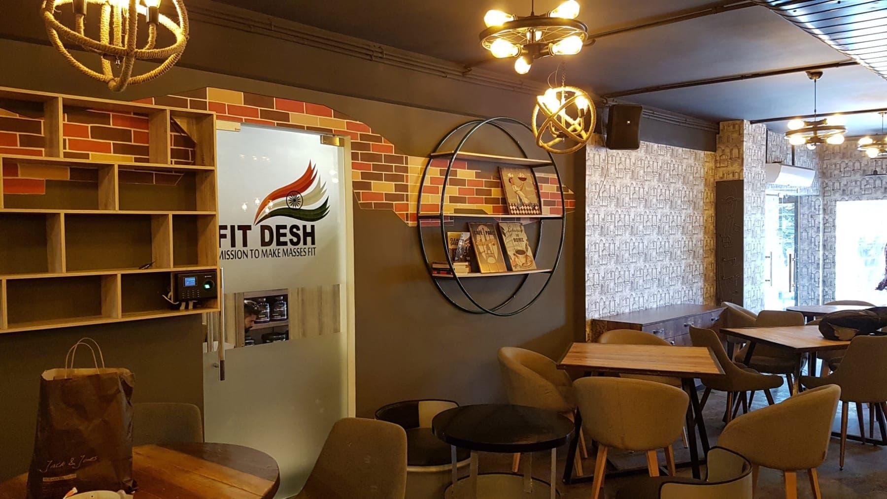 Circular metal shelf, brick-pattern wall and plush lounge seating at FiTreat restaurant, Ludhiana