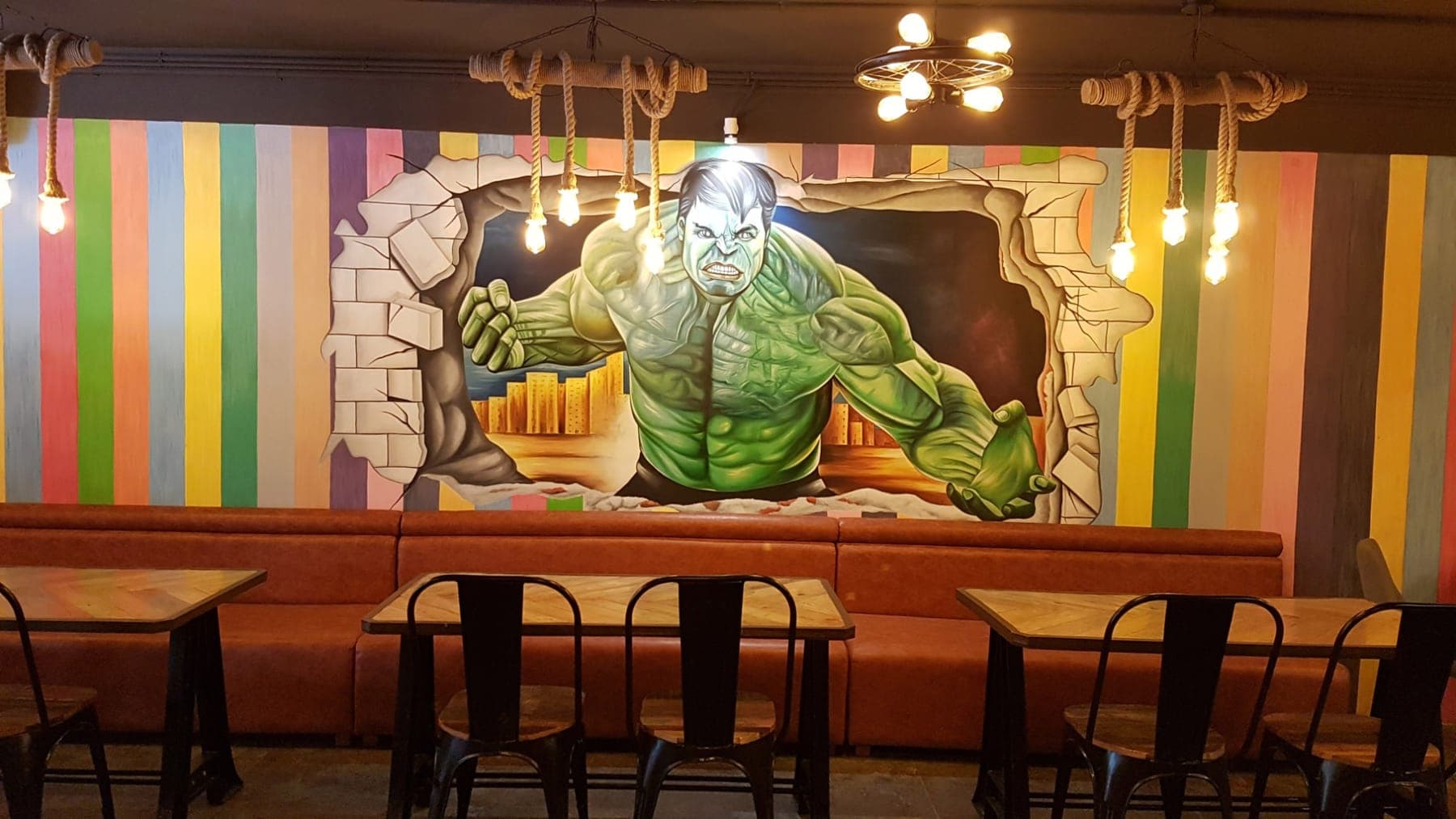 3D-style Hulk mural on a multicolour striped wall above tan booth seating at FiTreat restaurant, Pakhowal Road, Ludhiana