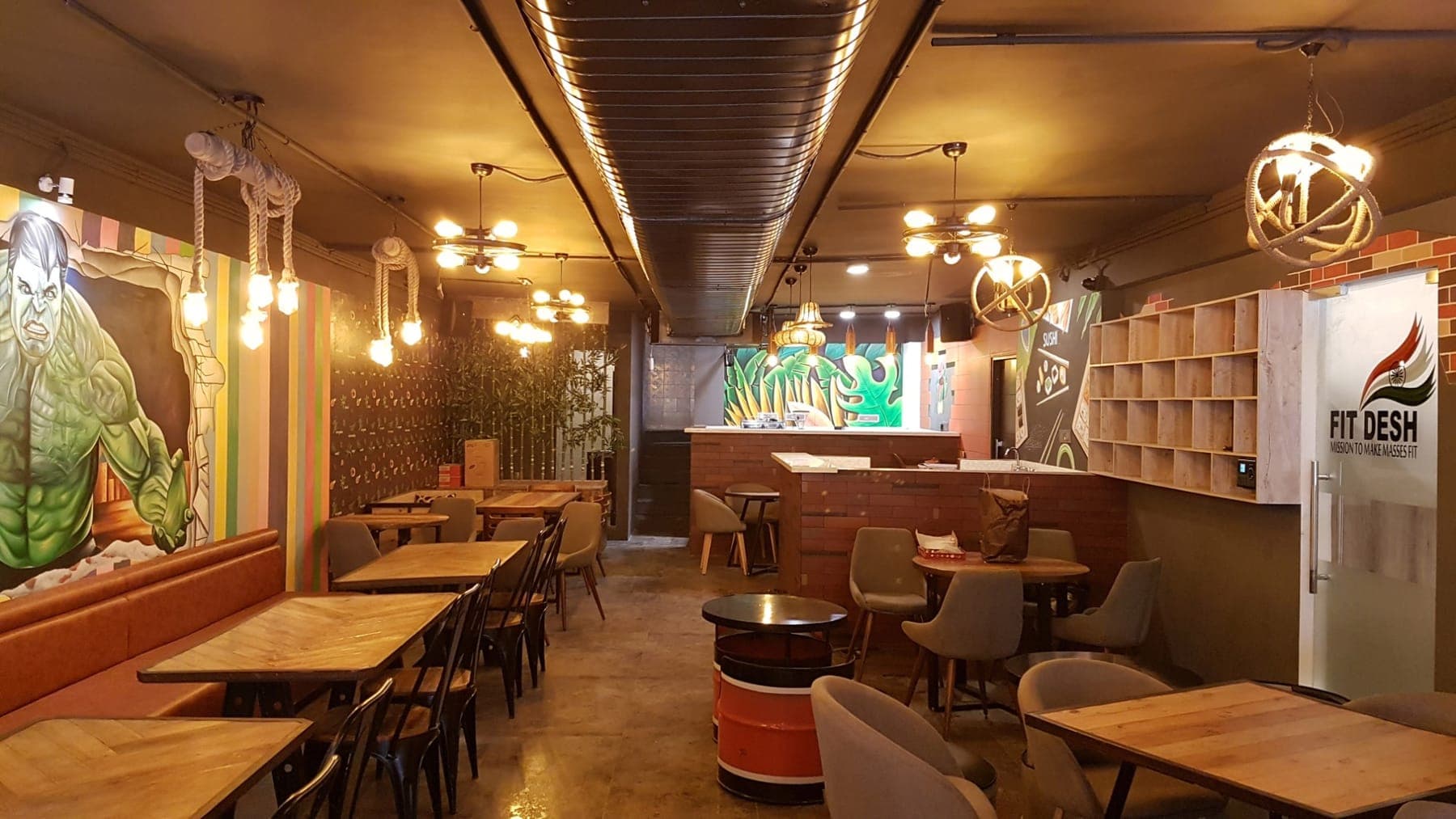 Seating zones with industrial metal chairs, lounge chairs and a brick accent wall at FiTreat restaurant, Ludhiana