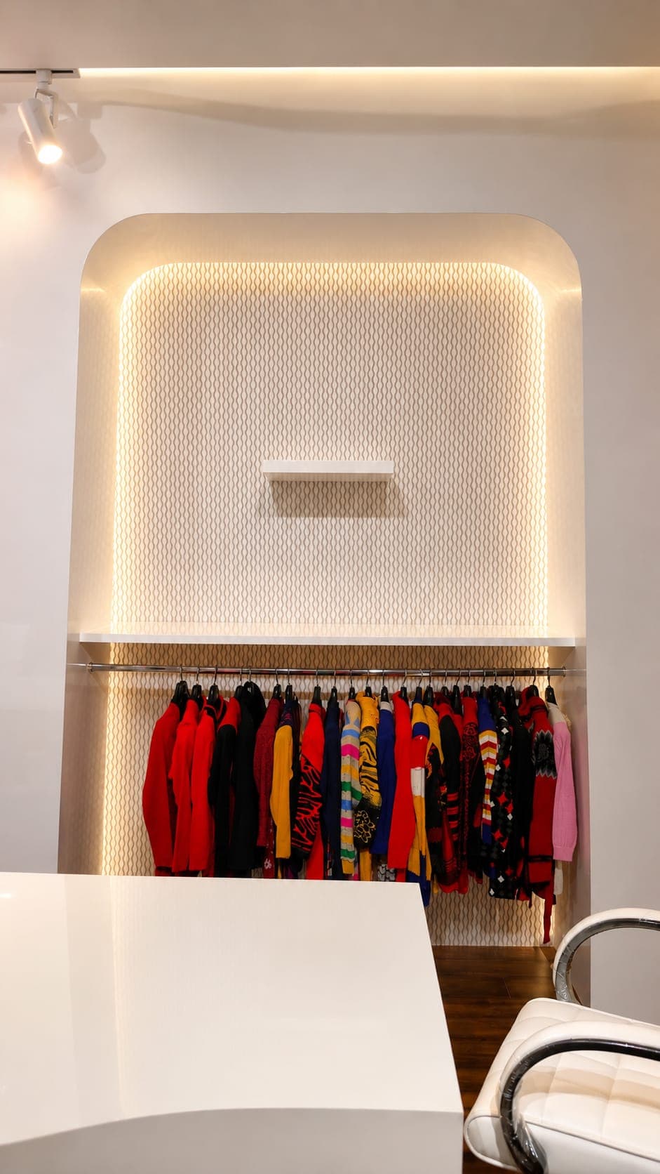 White-lacquer display alcove with LED cove lighting, track light and hosiery on a chrome rail, Ludhiana sample room