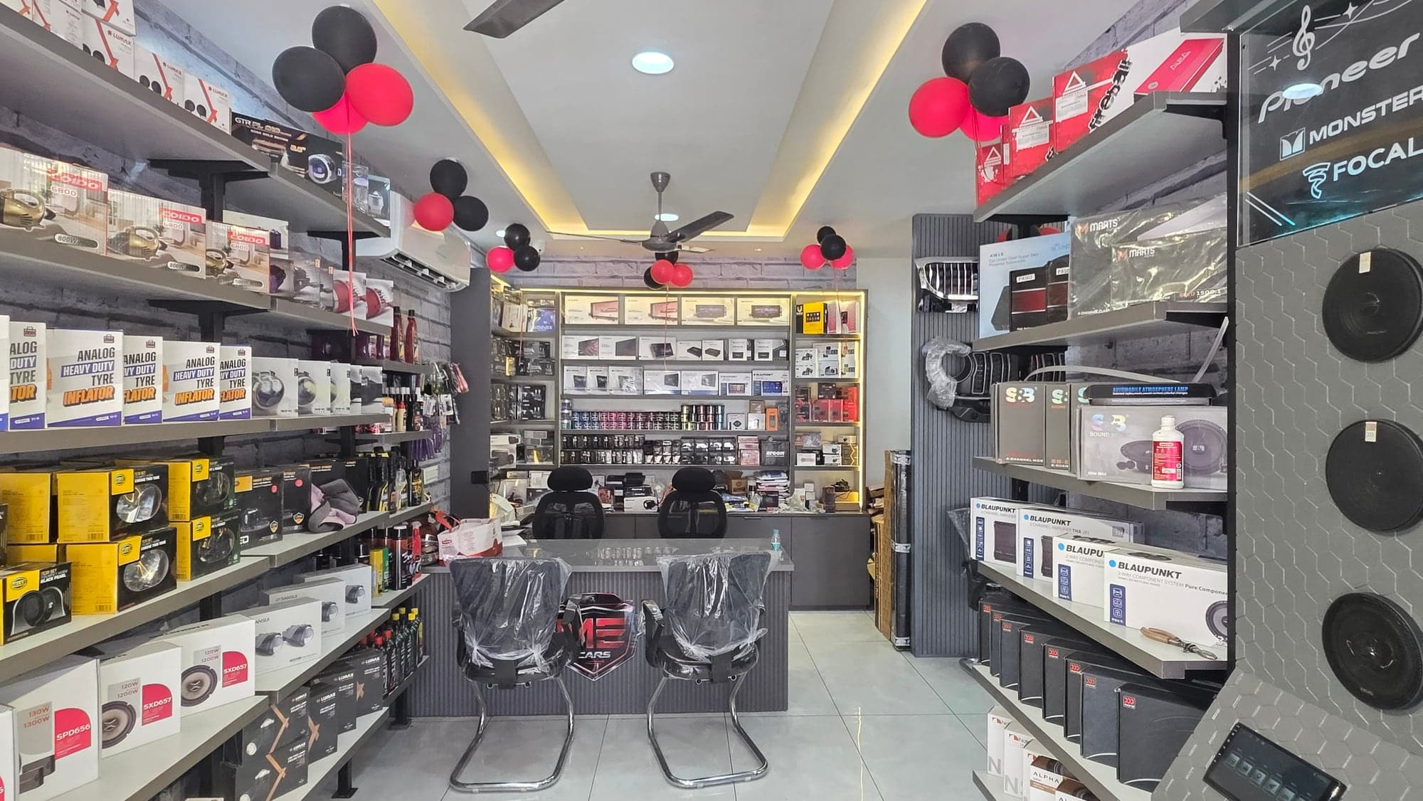 Malik Electronics car accessories showroom interior in Dugri, Ludhiana — grey brick walls, cove lighting and a honeycomb audio display wall