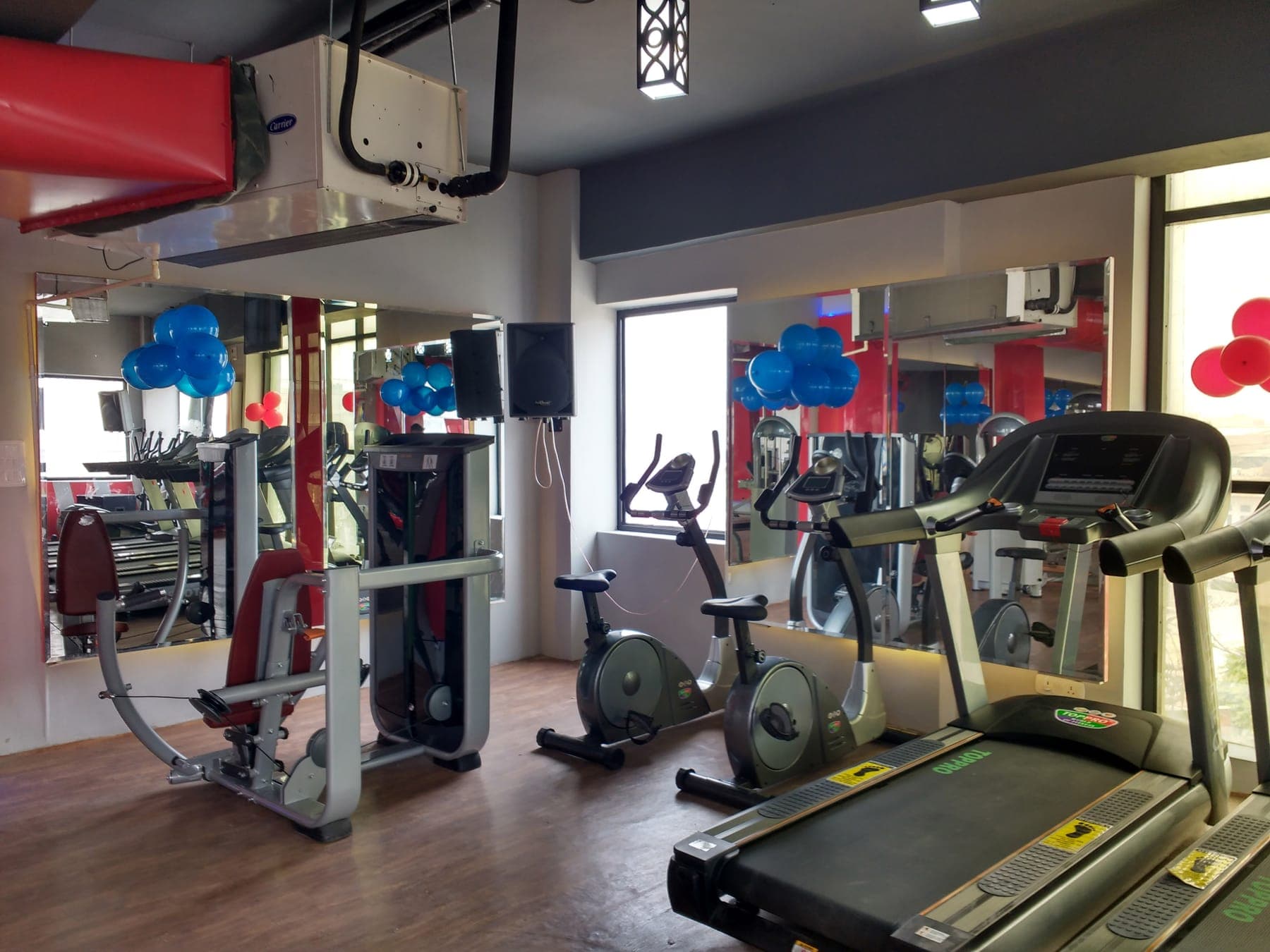Cardio zone with large mirrored walls and wood-finish flooring at Quillian Gymnasium, Ludhiana